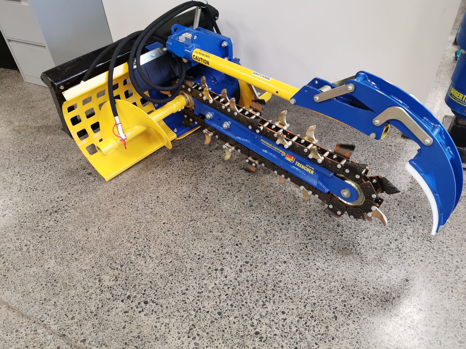 A blue and yellow machine is sitting on a concrete floor.