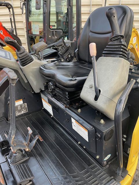The inside of a small excavator with a seat and controls.