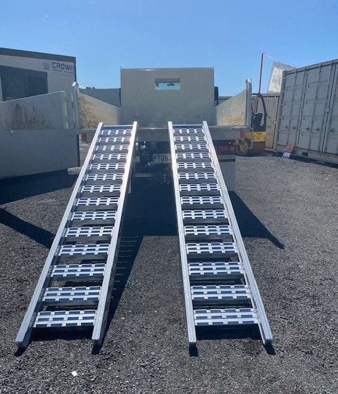 A truck with ramps attached to it is parked in a parking lot.