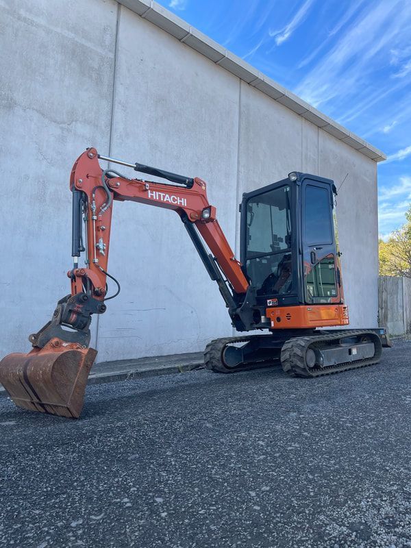 A small excavator is parked in front of a building.