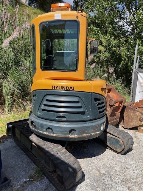 A yellow and gray hyundai excavator is parked on the side of the road