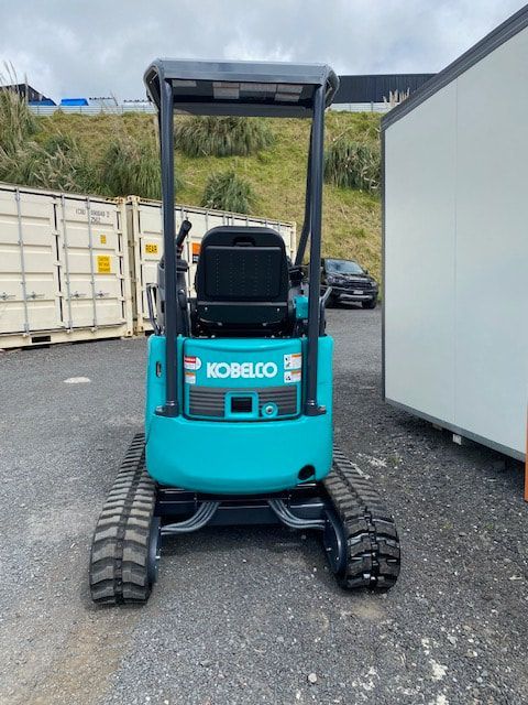 A blue kobelco excavator is parked in a parking lot