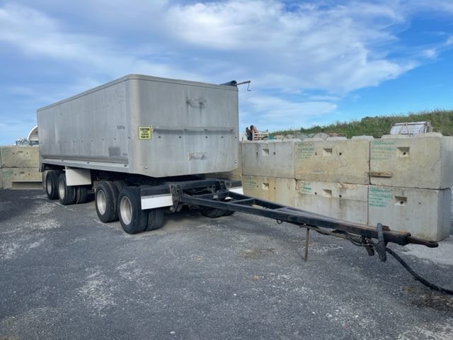 A semi truck is pulling a trailer with concrete blocks attached to it.