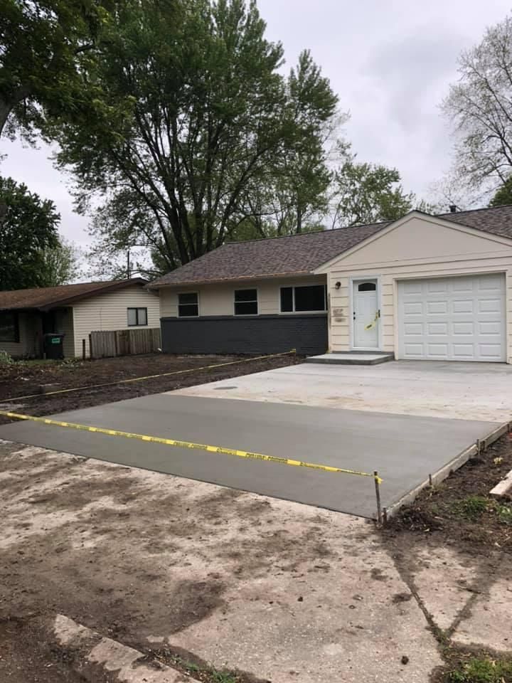 Single-story house with a white garage, concrete driveway, and trees in the yard