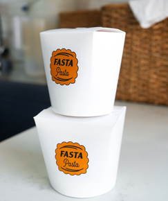 Two stacked white takeout cups with orange Fasta Pasta logos on a table