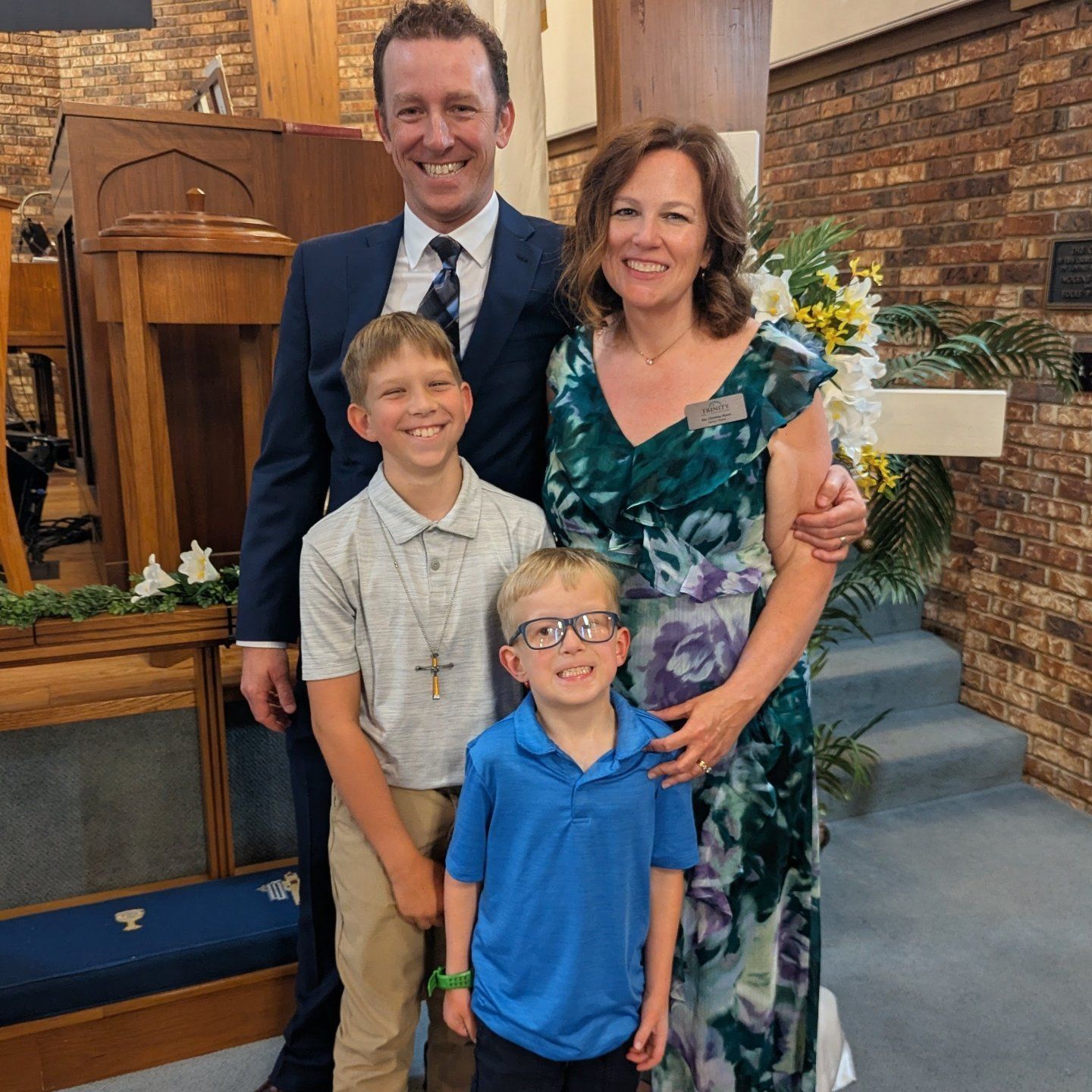 Family of four posing in a church, with a man and woman behind two boys, all smiling.