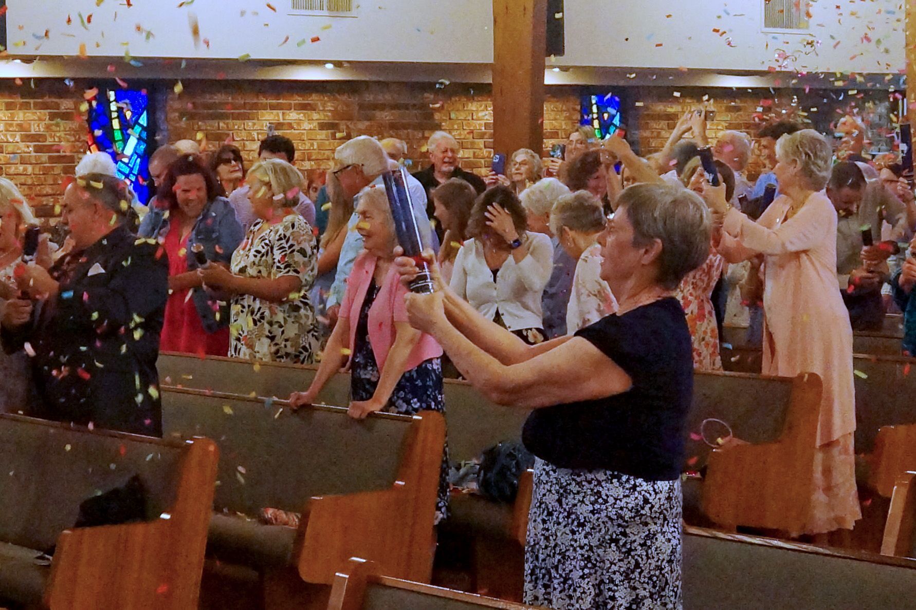 People in a church pew tossing colorful confetti during a celebration of Easter