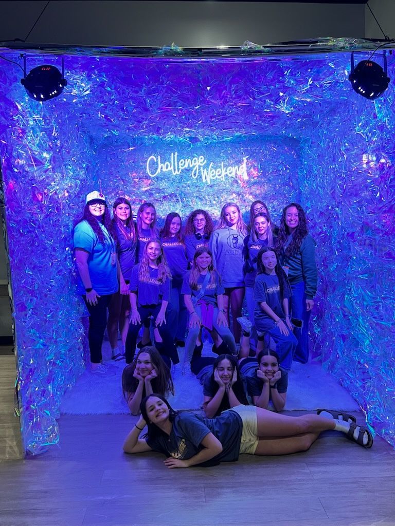 Group posing in a glowing blue photo booth with a neon sign and sparkling backdrop