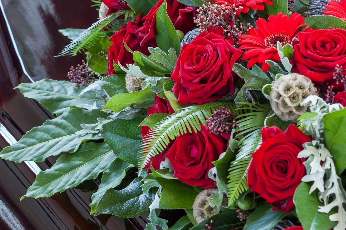 Pink and yellow flowers in a red vase on a windowsill