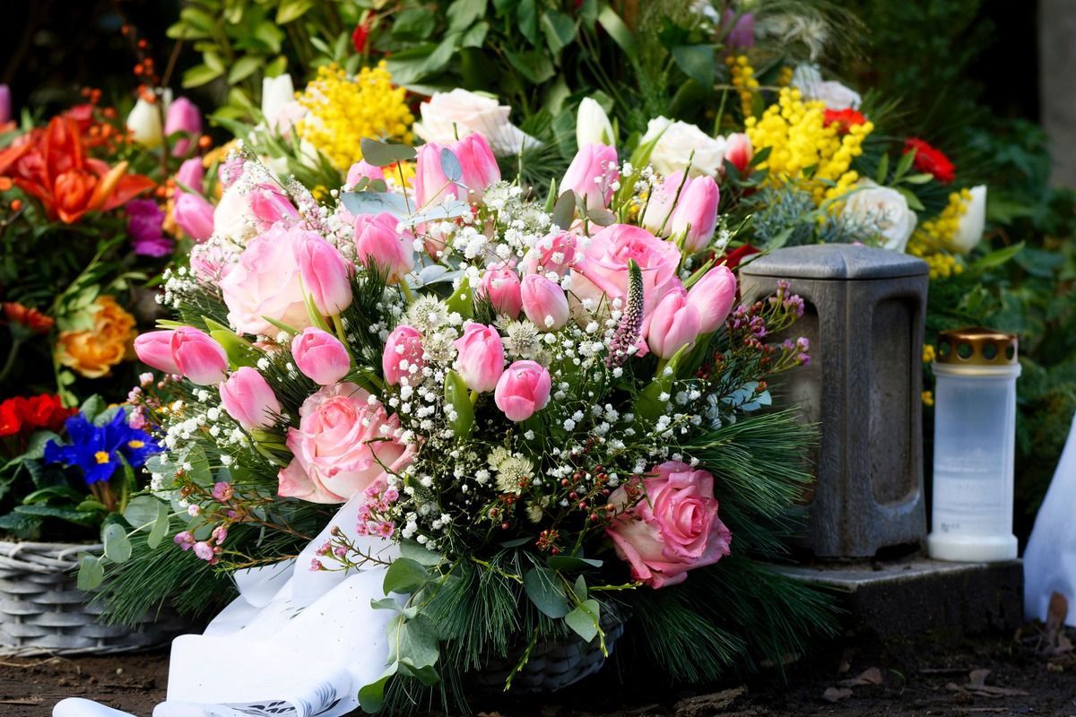 Pink rose bouquet at a gravesite, surrounded by colorful flowers and a memorial plaque