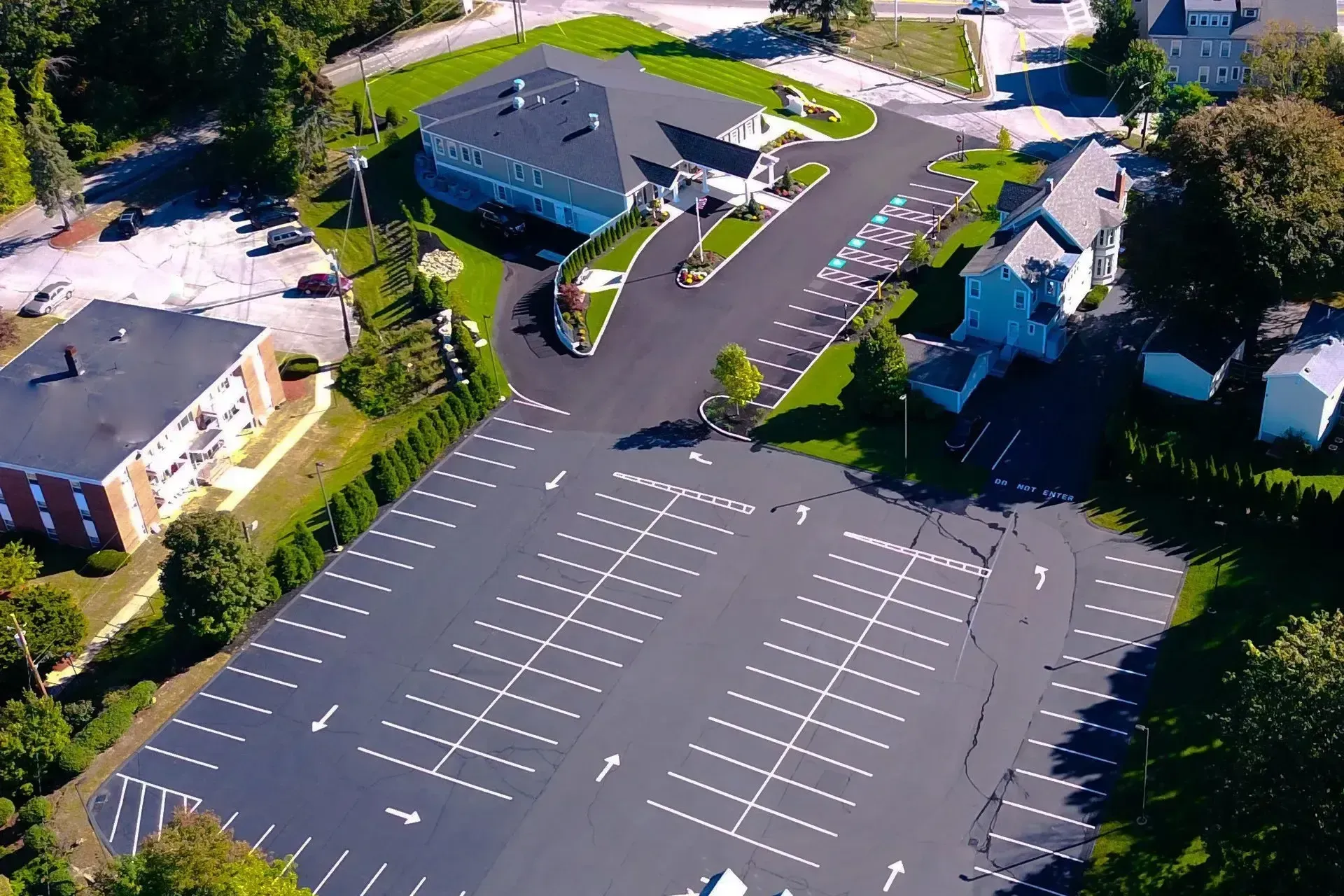 Aerial view of an empty parking lot beside buildings and trees on a sunny day
