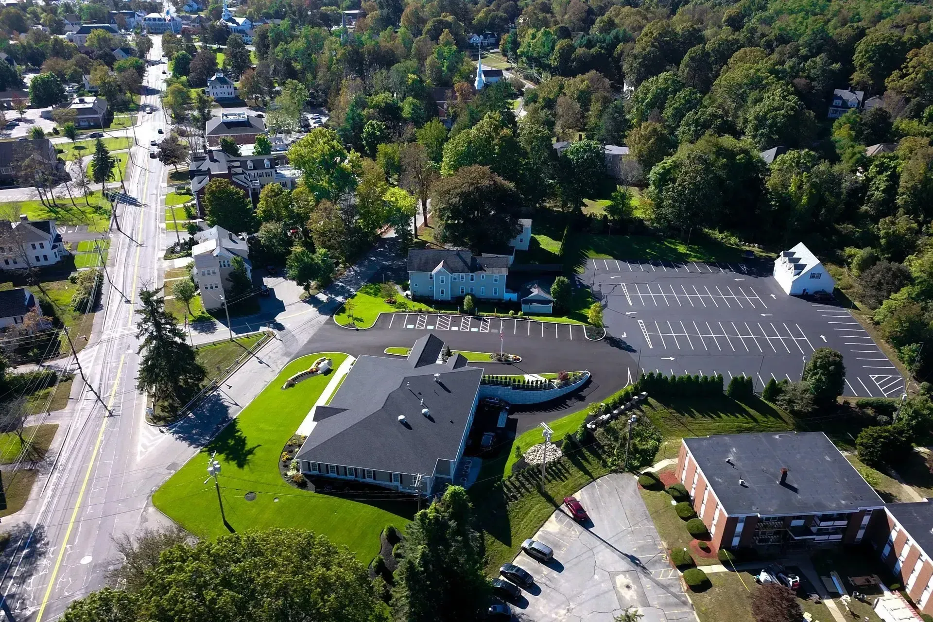 Aerial view of a suburban office complex with parking lots, roads, and surrounding trees