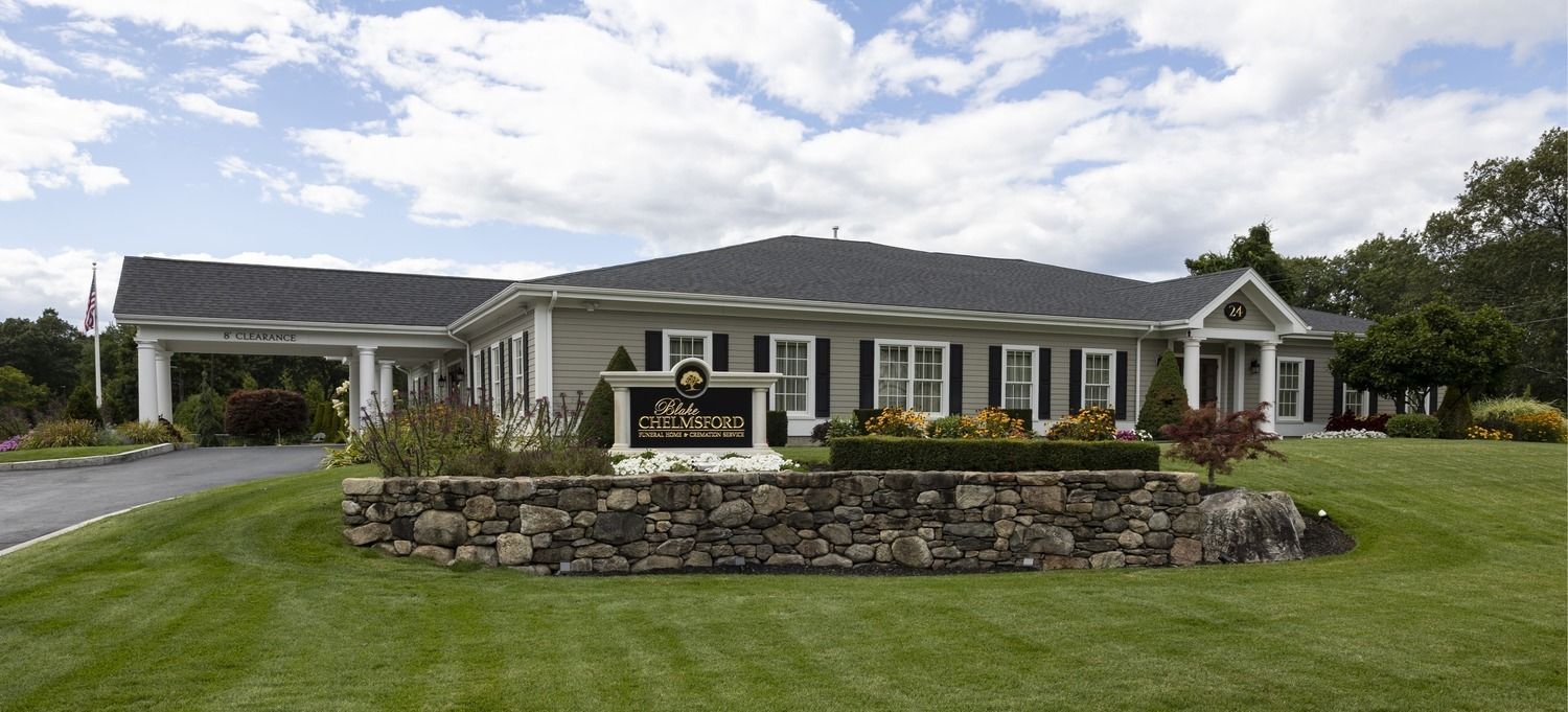 Single-story house with a stone facade, manicured lawn, and cloudy sky