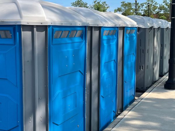 Row of blue portable toilets lined up outdoors on a sunny day
