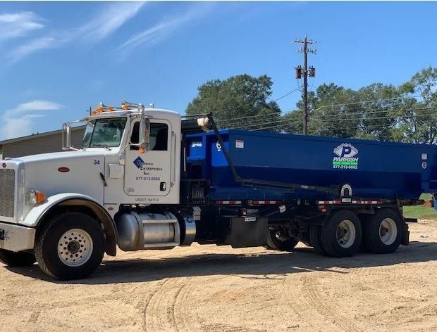 A dump truck is parked in a dirt field.