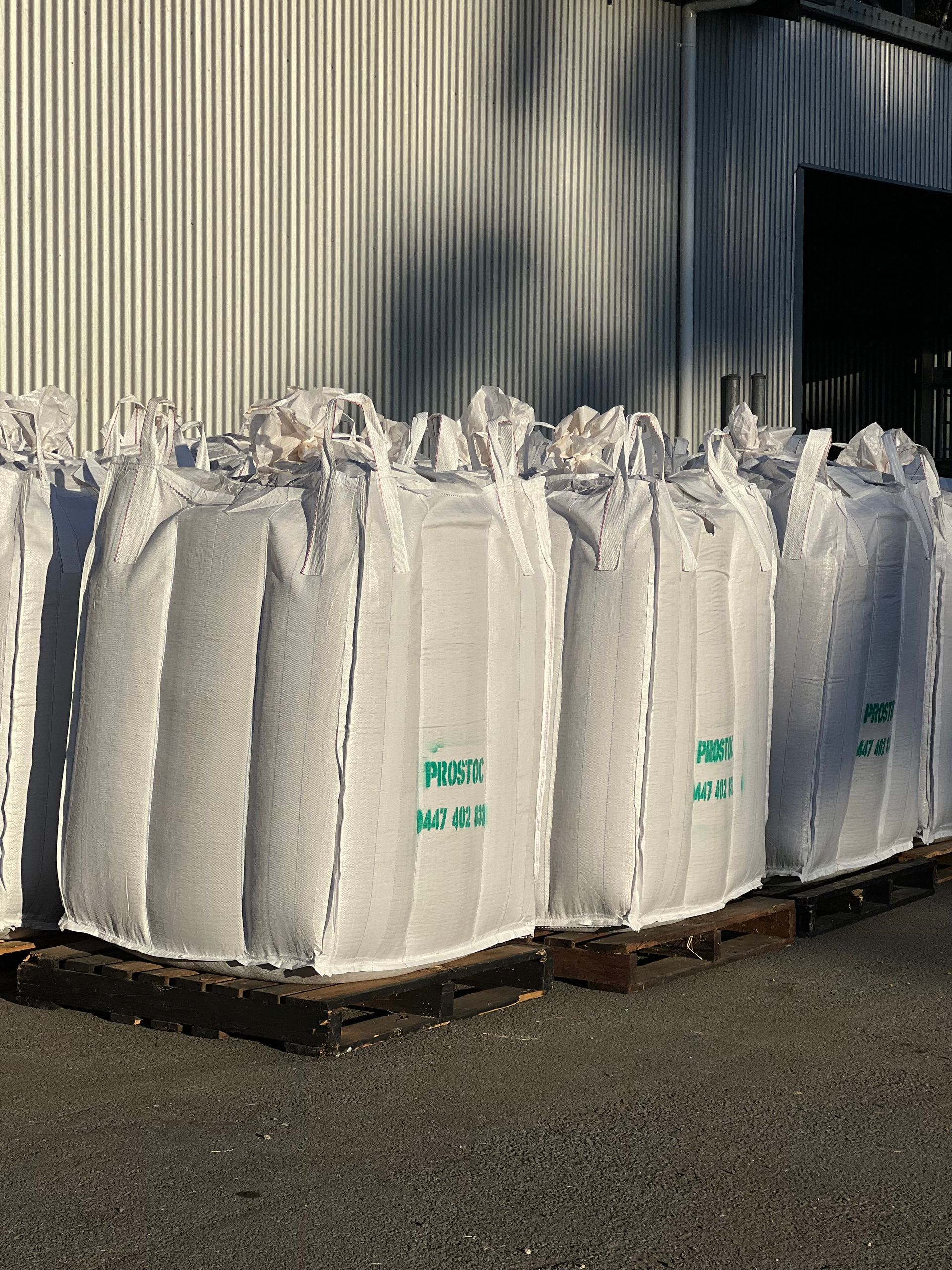 Large White Sacks, Filled, on Wooden Pallets, Against a Corrugated Metal Wall — Prostoc In South Kempsey, NSW