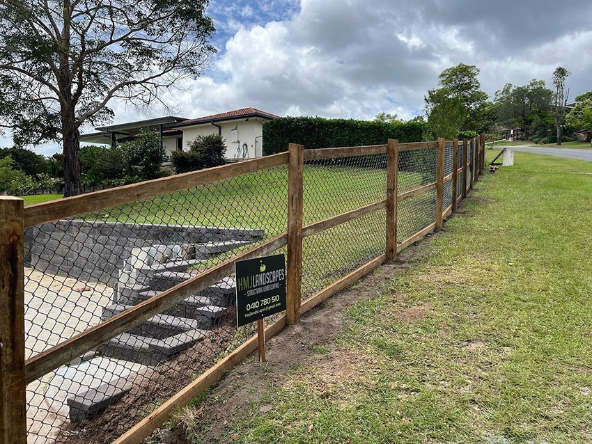 A Wooden Fence with a Chain Link Fence — HMJ Landscapes in Robina, QLD