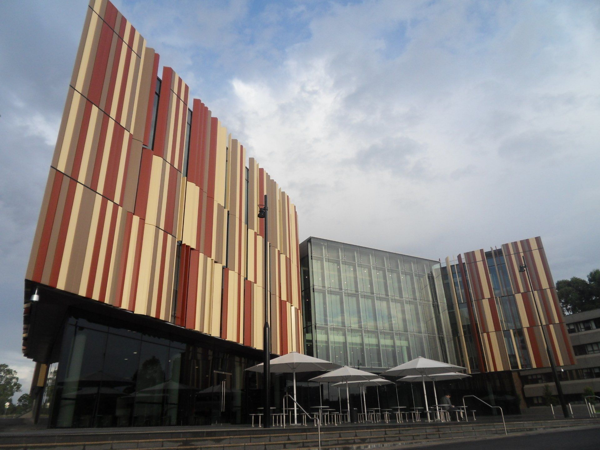 A large building with a lot of windows and umbrellas in front of it