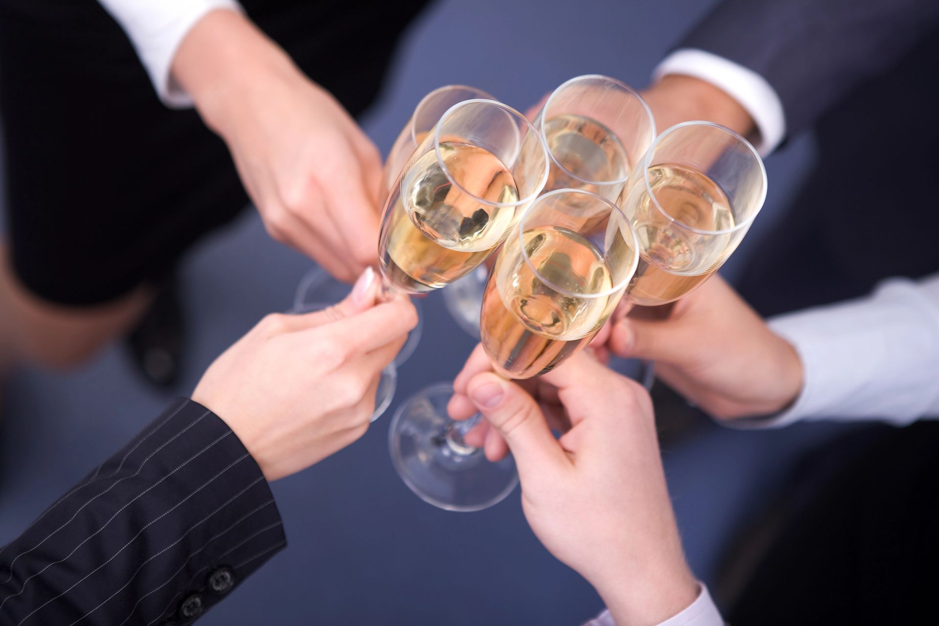 Mani che tengono calici da champagne, brindando insieme, in un momento di festa.
