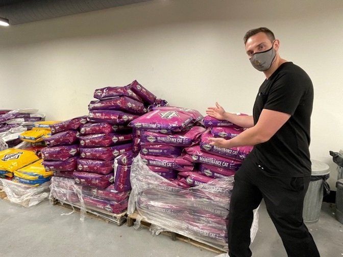 Doctor Andrew Vallo is standing next to pallets of dog food.