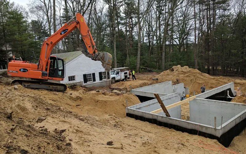 Orange excavator digging at a house foundation construction site with concrete basement walls and dirt piles
