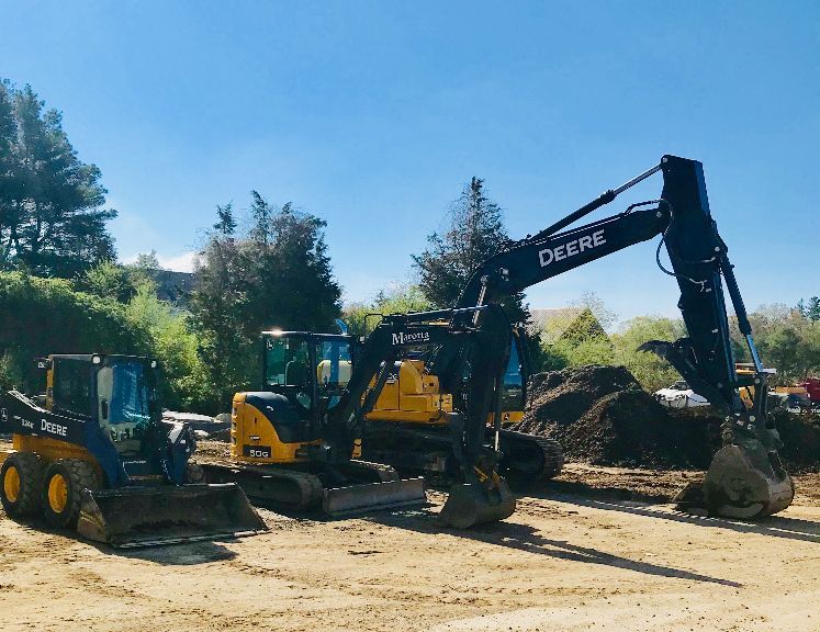 Yellow excavator and loader at a dirt construction site on a sunny day