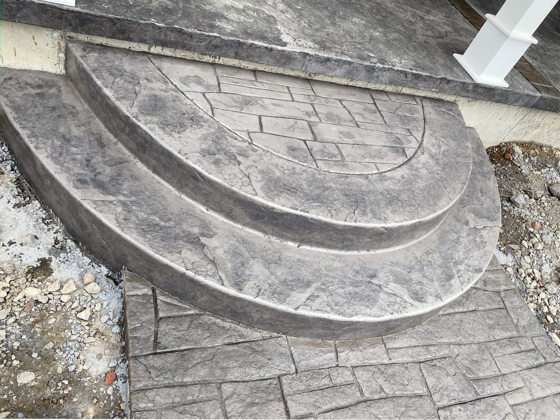 Curved concrete steps with a textured brick walkway beside a building entrance