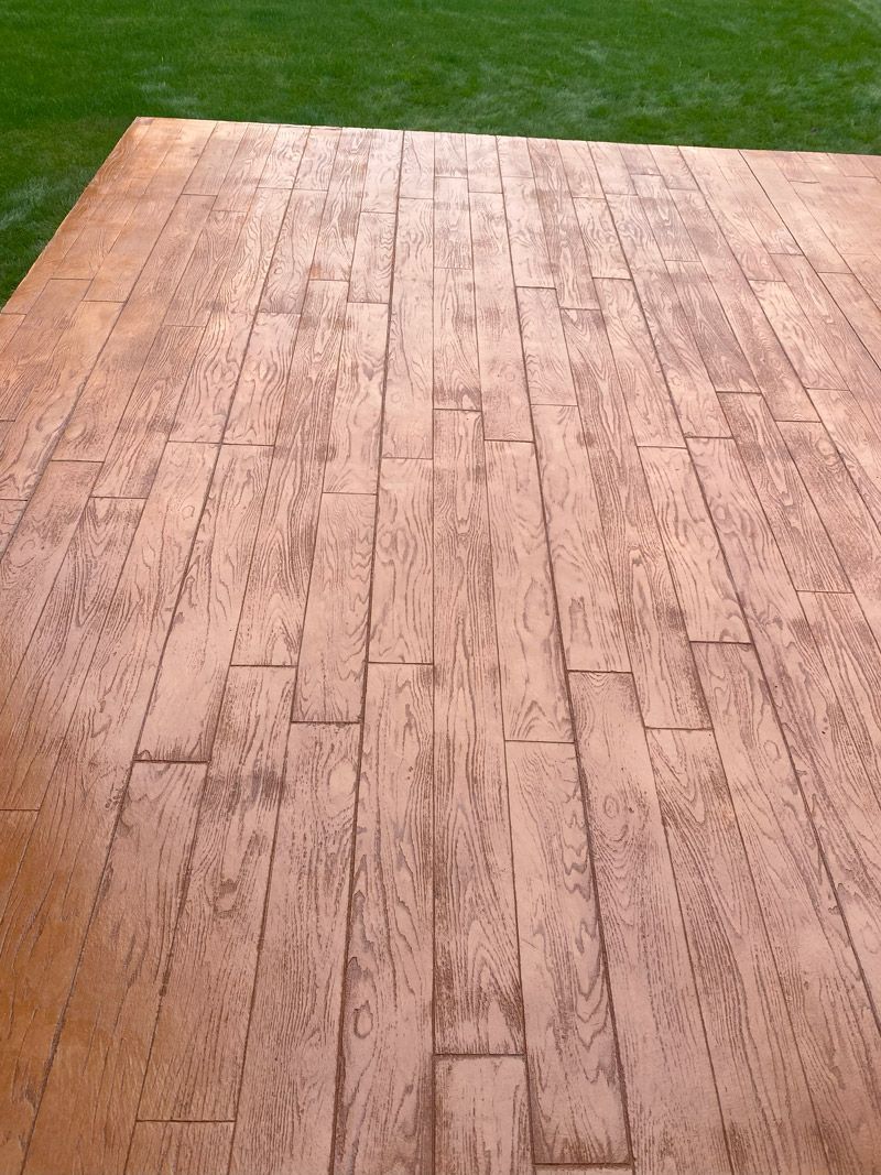 Wooden deck with light brown planks beside a green lawn
