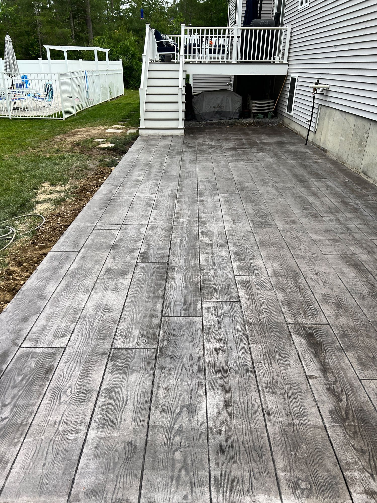 Weathered wooden driveway leading to a raised deck with stairs beside a house