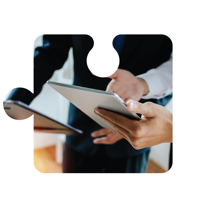 Hands holding tablets during a business meeting, shown in a puzzle-piece frame