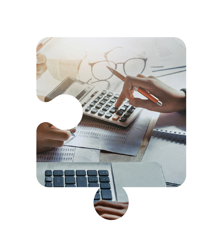 Hands using a calculator and a laptop on paperwork, with glasses nearby on a desk.