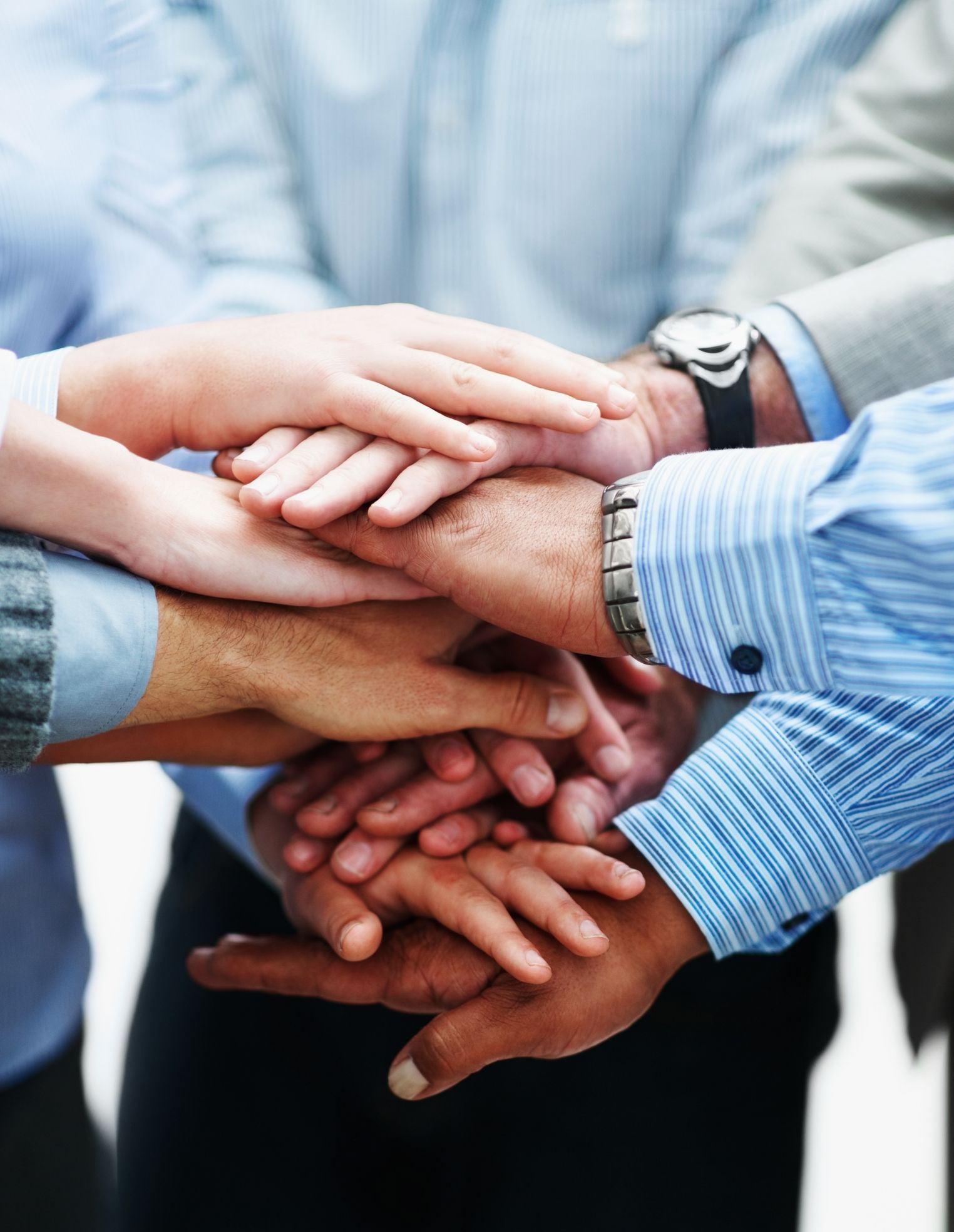 Hands of diverse people stacked together in a team huddle, symbolizing unity and teamwork.