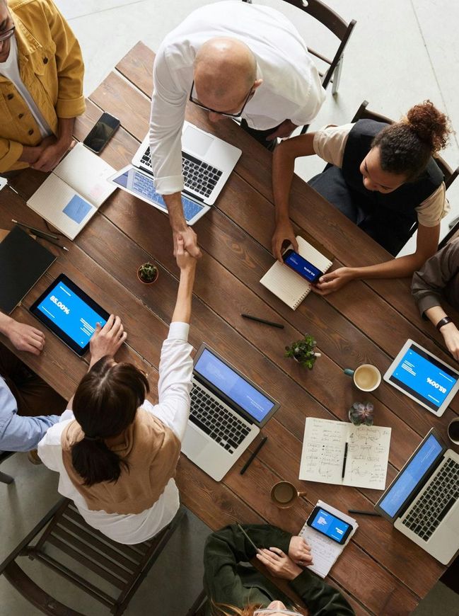 A group of people are sitting around a table shaking hands.