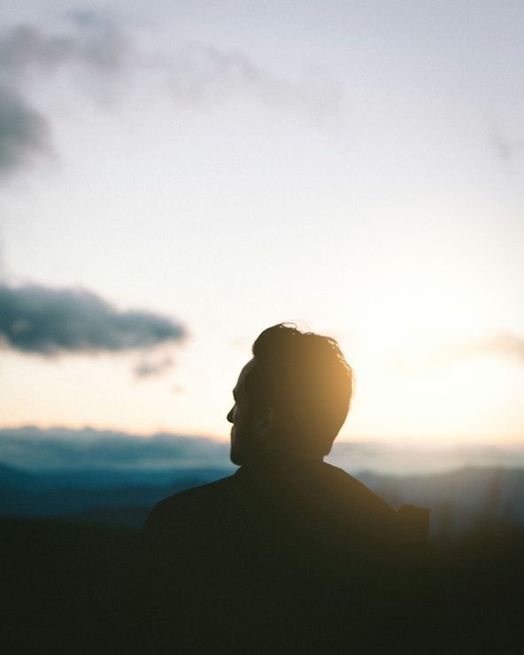 A silhouette of a man standing in front of a sunset.