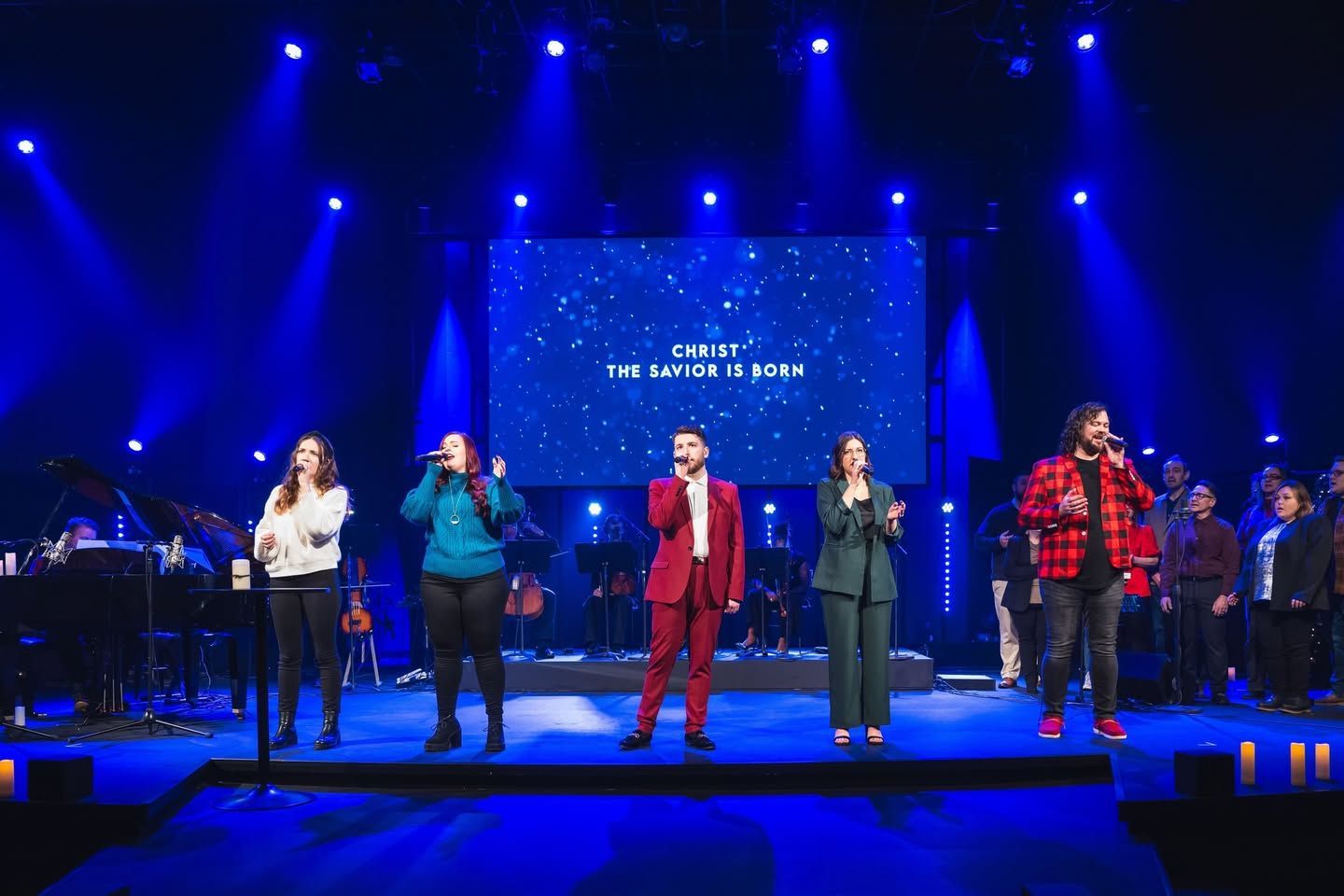 House of Worship AV solutions. A choir of singers on stage performing under blue lights. A screen with text behind them.
