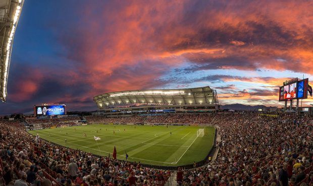 Stadium AV soltuions. Soccer stadium filled with fans during sunset; red and orange sky, green field.