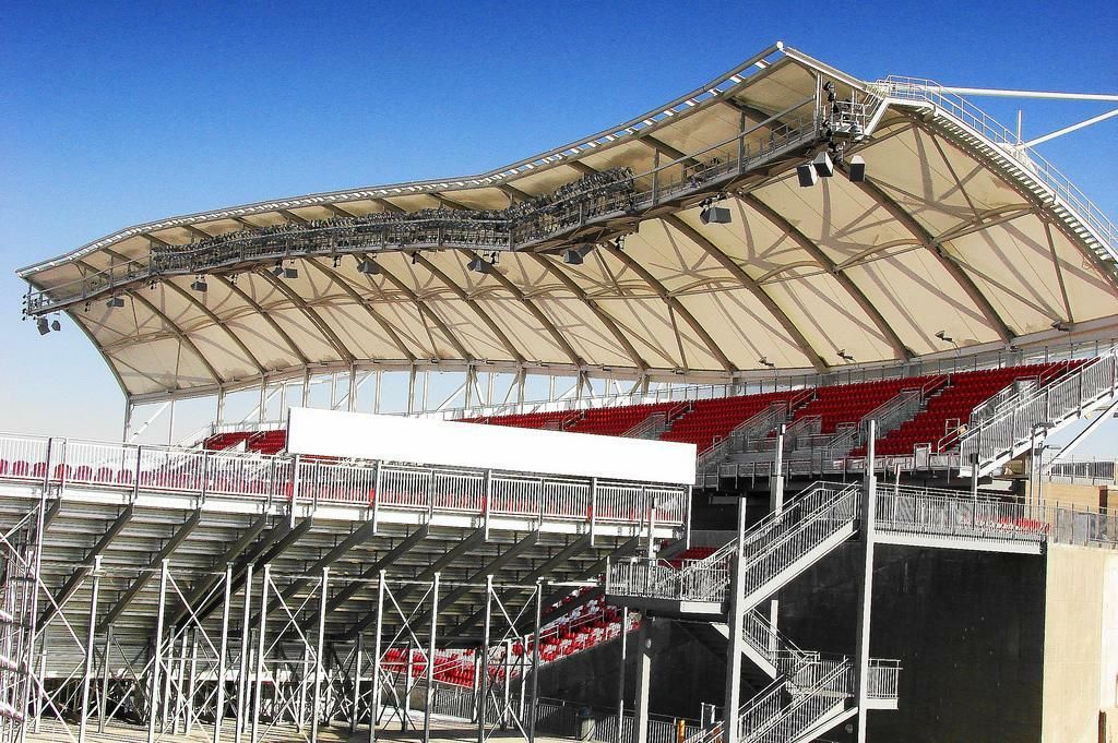 Stadium AV soltuions. White speaker system suspended from a dark ceiling.