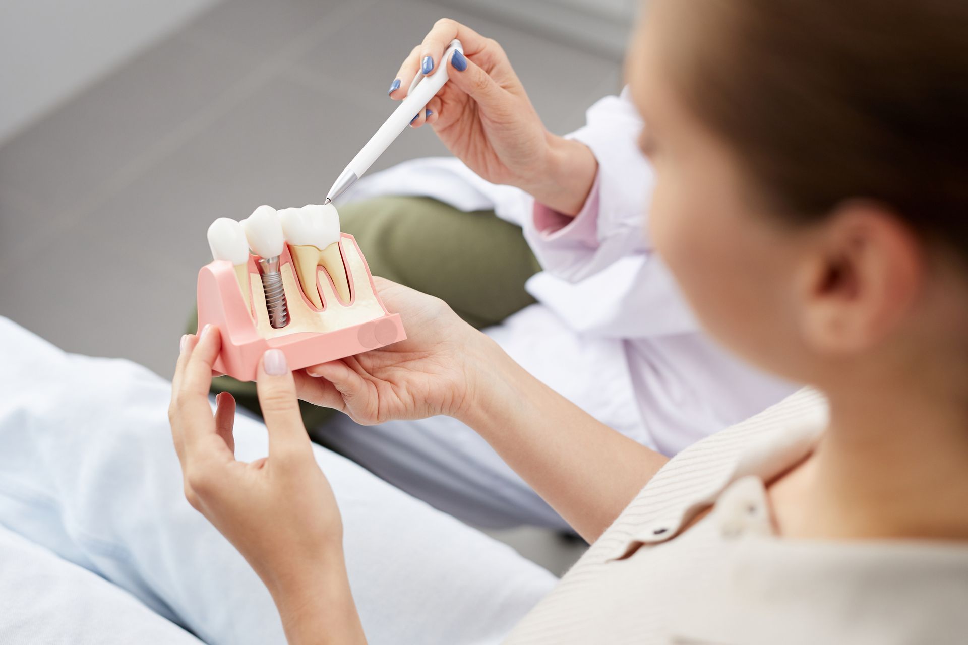 Dentist showing a patient a model of dental implants.