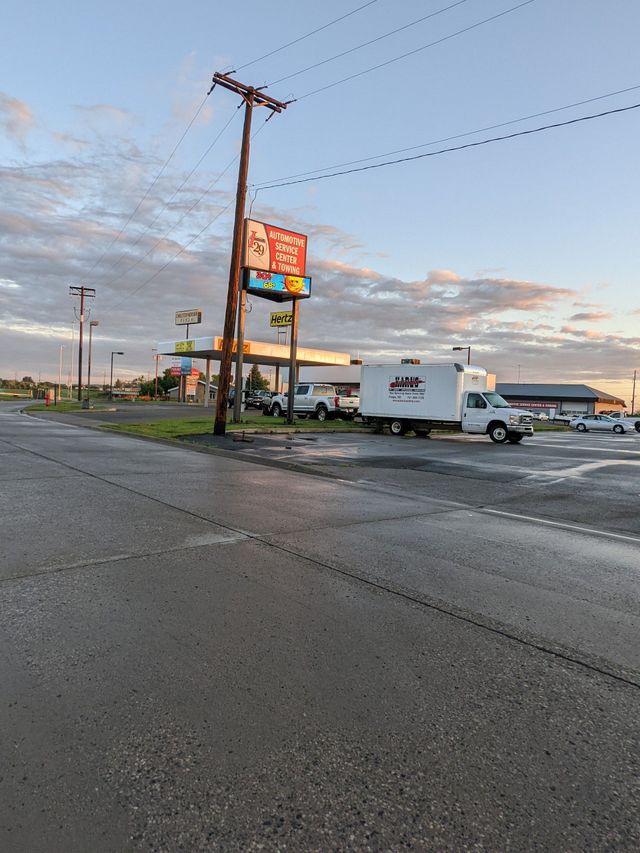 Dawn at a roadside gas station and convenience store, with a white delivery truck parked outside. | I29 Automotive Repair