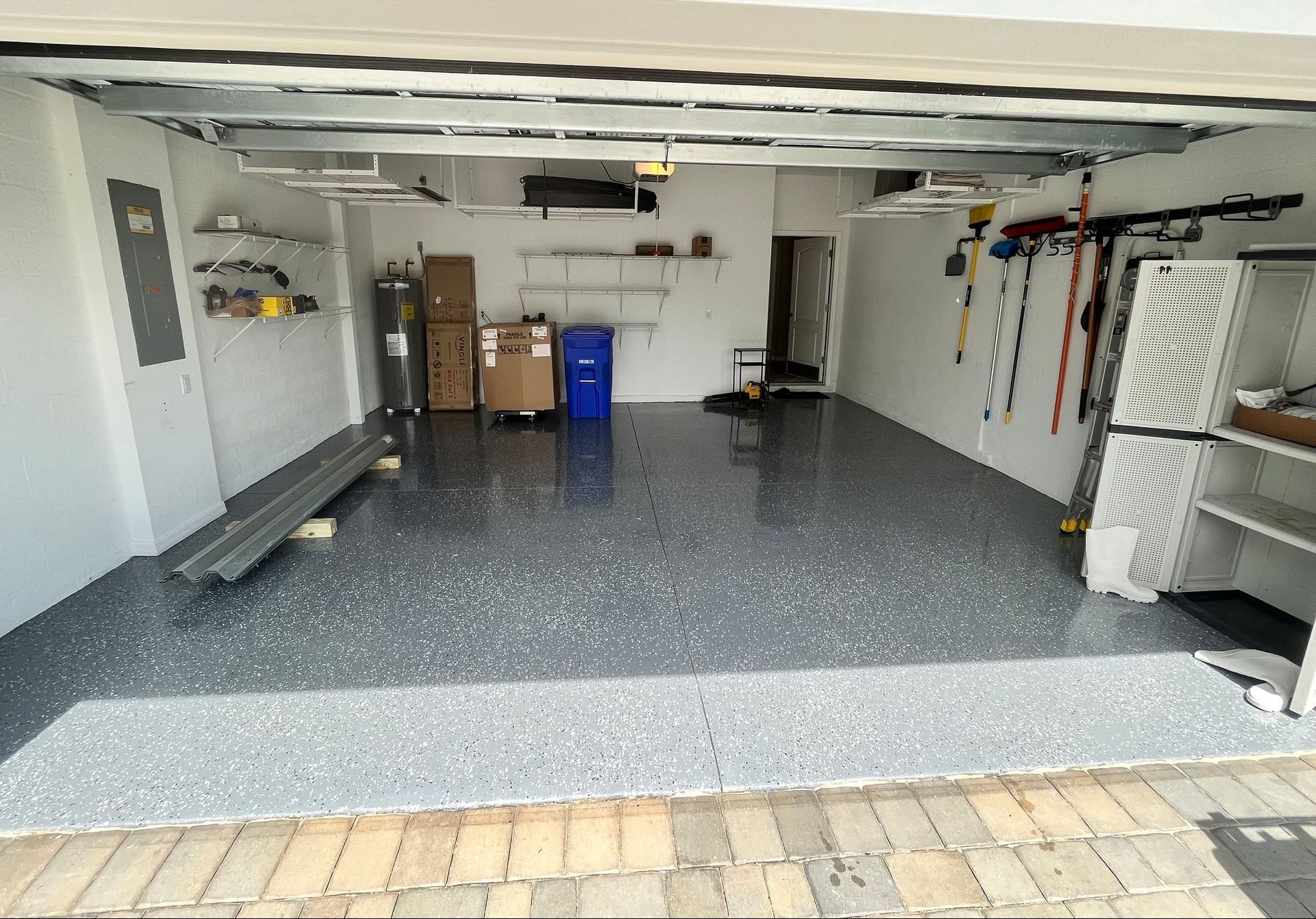Garage interior with a gray epoxy floor. Boxes, shelves, and tools are visible.