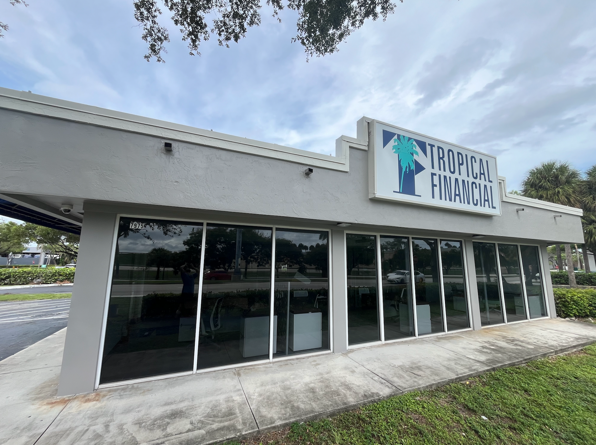 Exterior view of a Tropical Financial branch, gray building with large windows and sign.