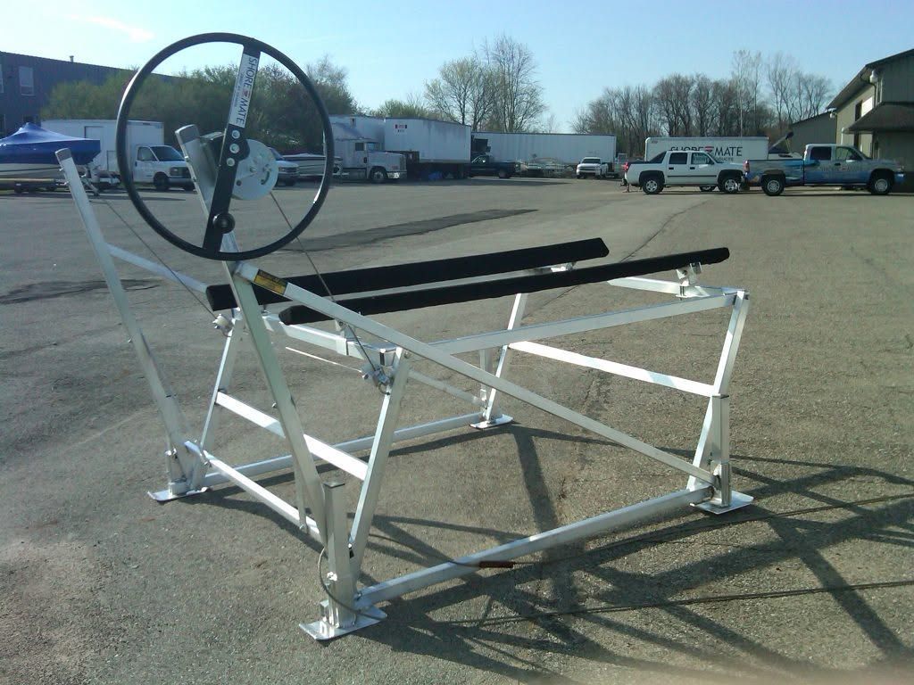 White metal wheelchair lift platform with a large wheel, parked outdoors on a lot.