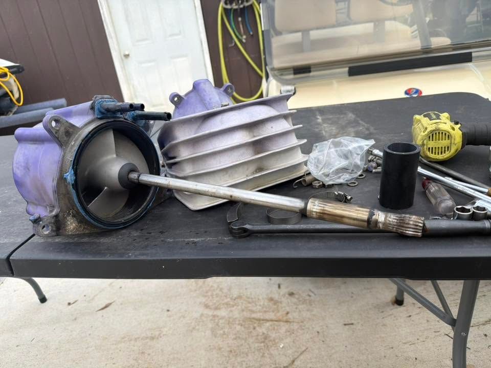 Turbine engine parts and tools laid out on a workbench in a garage.