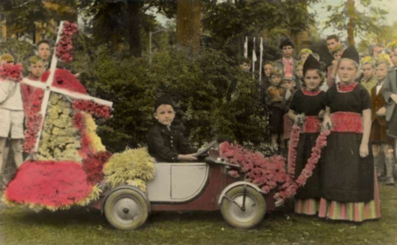 Een groepje kinderen staat naast een met bloemen versierde auto.