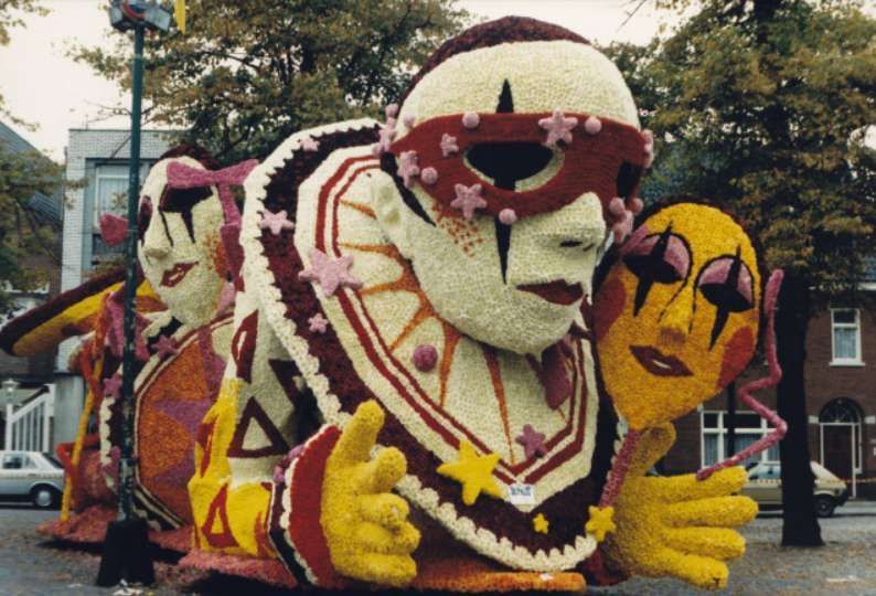 Een clown gemaakt van bloemen houdt een masker vast