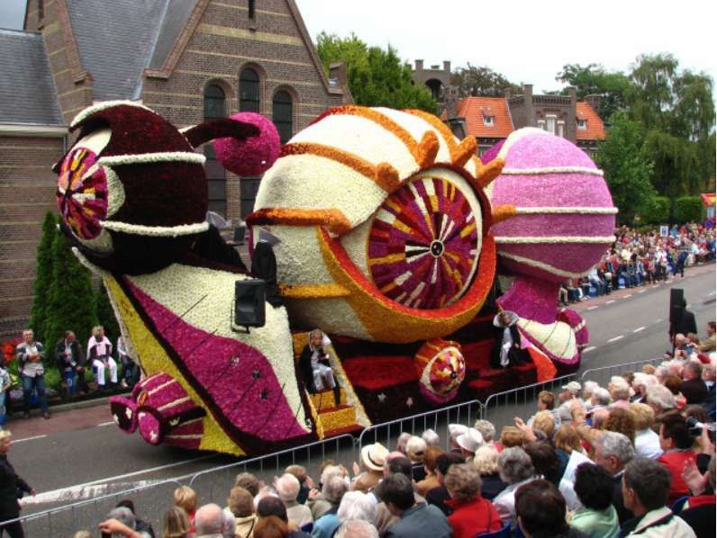Een parade met een praalwagen die op een slak lijkt