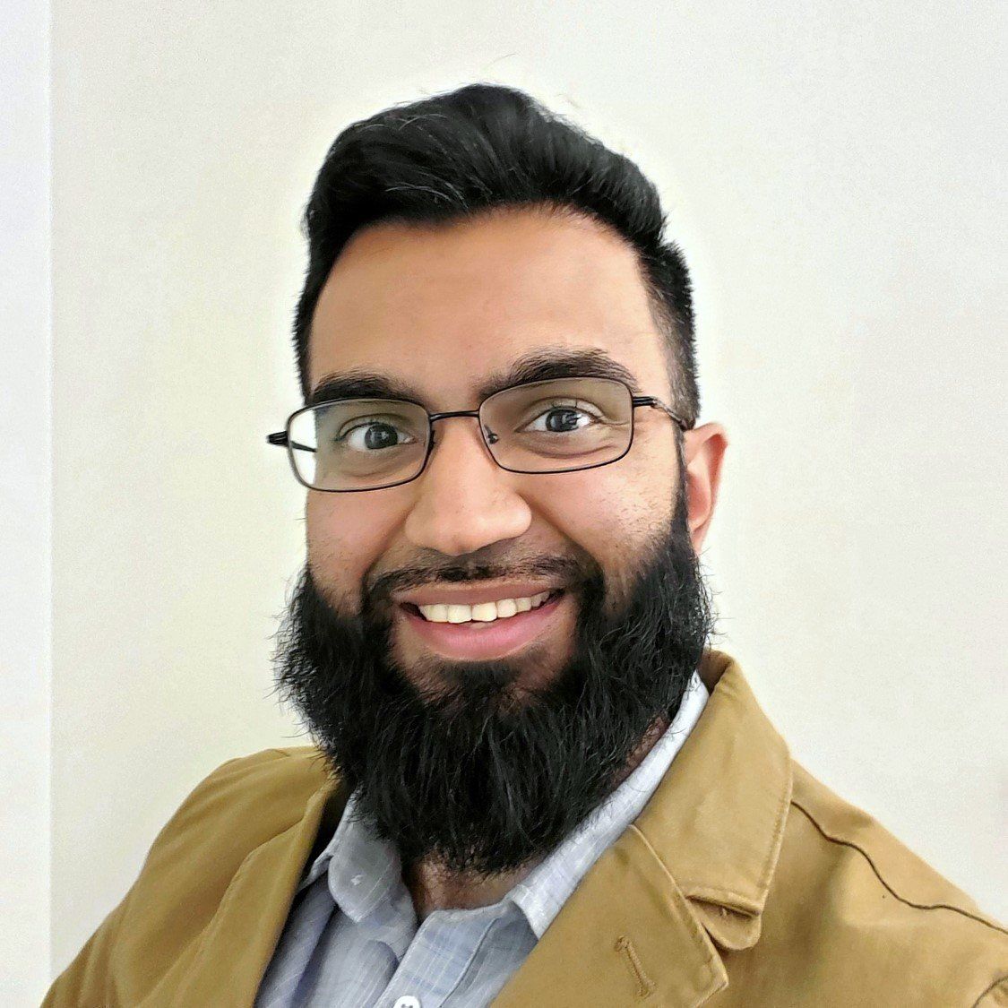 A man with a beard and glasses is smiling for the camera.