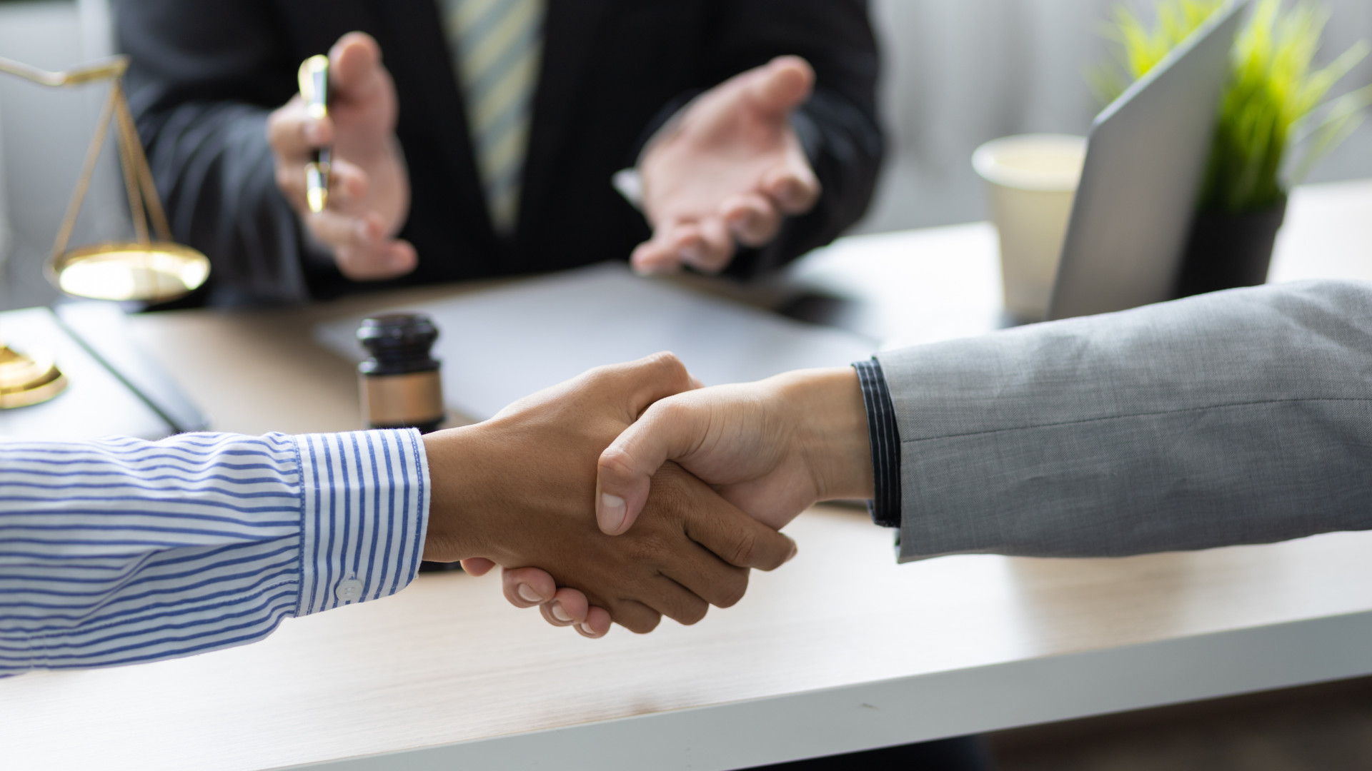A man and a woman are shaking hands in front of a lawyer.
