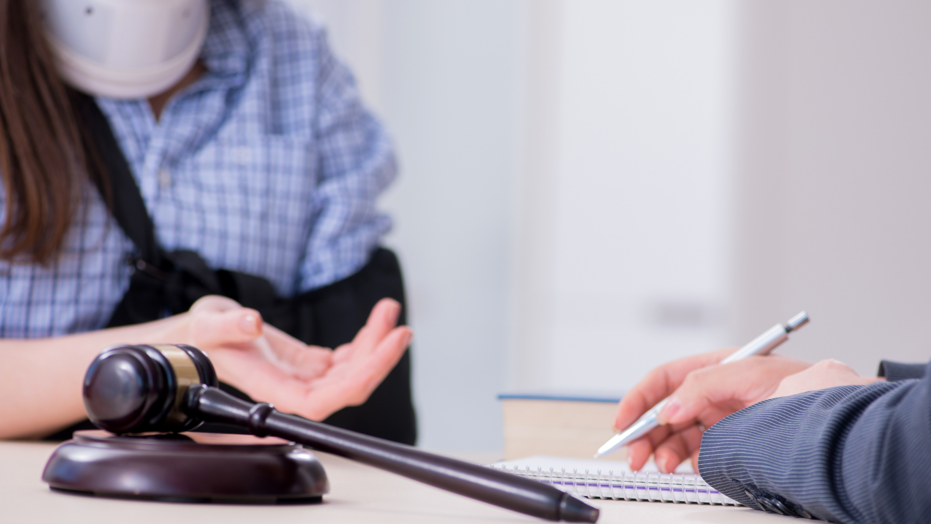 A woman in a wheelchair is sitting at a table with a judge 's gavel.