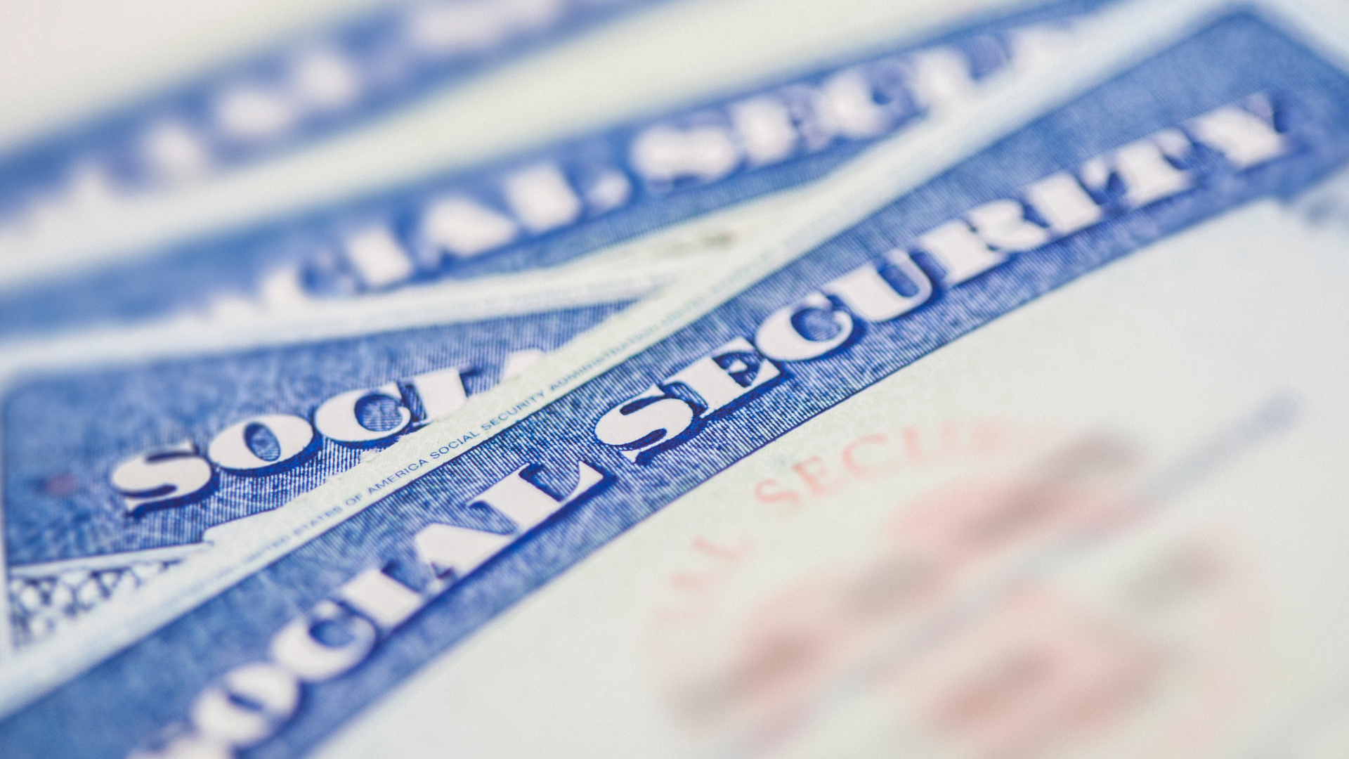 Three social security cards are stacked on top of each other on a table.
